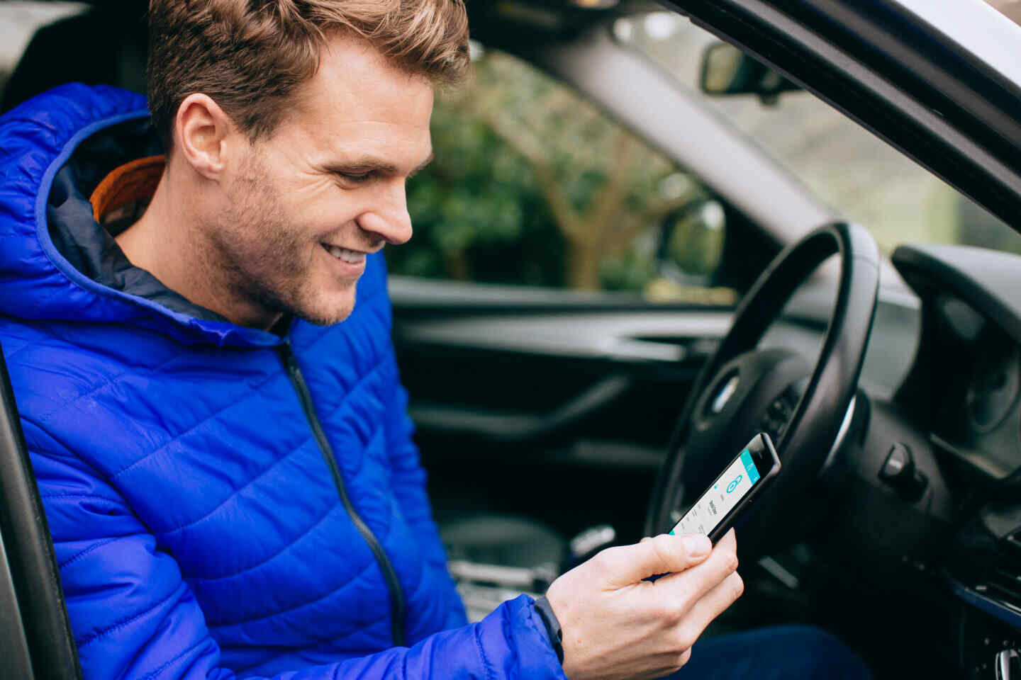 man in car looking at kubu app